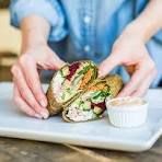 a person is holding a sandwich on a plate