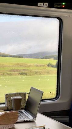 a woman sitting at a table with a laptop computer on her lap looking out the window