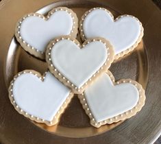 four heart shaped cookies are on a plate