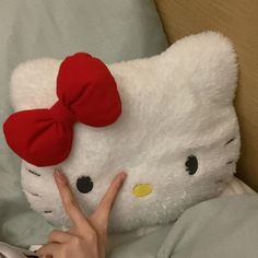 a person is laying in bed with a large hello kitty stuffed animal on their hand