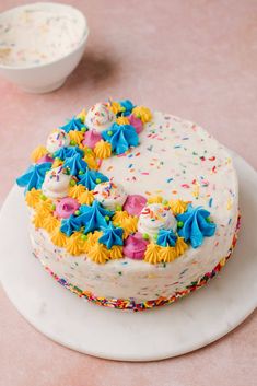 a birthday cake with sprinkles and frosting on a white platter