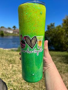 a person holding up a green cup with some liquid in it and the words i love beer on it