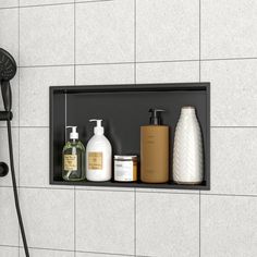 a shower head with soap, shampoo and lotion bottles on the shelf next to it