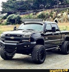 a black truck parked on top of a dirt road