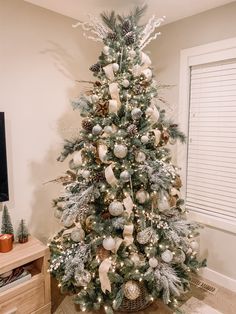 a decorated christmas tree in the corner of a living room with white and silver decorations