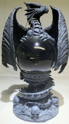 a black dragon sculpture sitting on top of a white table next to a mirror ball