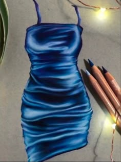 a drawing of a blue dress next to some crayon pencils and lights