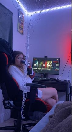 a woman sitting in a chair holding a wine glass next to a computer monitor and keyboard