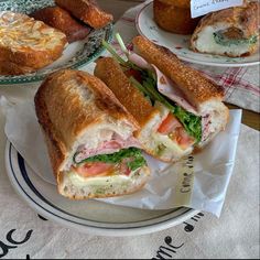 two plates with sandwiches and pastries on them