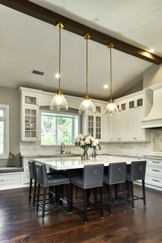 a large kitchen with white cabinets and wooden floors