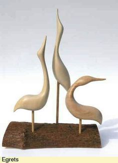 two white birds are standing on top of a piece of wood with sticks in the shape of an egret