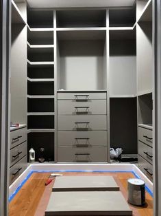 an empty walk in closet with lots of drawers and lights on the floor next to it