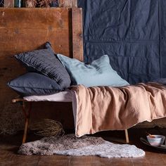 a bed with several pillows on top of it next to a plate and bowl filled with fruit