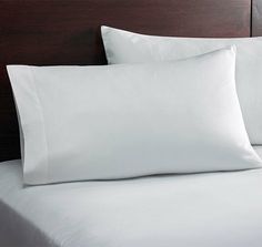 a bed with white sheets and pillows on it