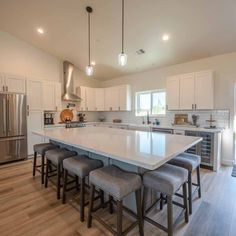 a large kitchen with an island in the middle and four stools at the end