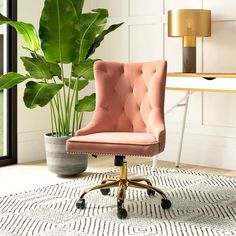 a pink office chair sitting on top of a rug next to a potted plant