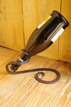 a wine bottle that is sitting on the floor next to a wall mounted iron hook