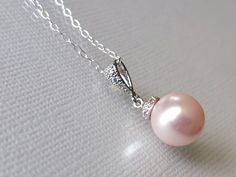 a pink pearl and diamond pendant on a silver chain with a white bead around it