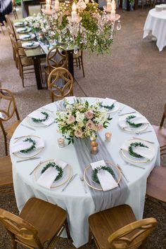 the table is set with white linens and greenery