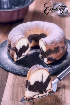 a bundt cake is cut in half on a black plate with a spatula