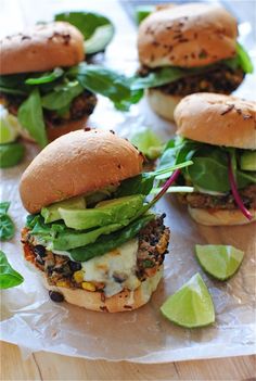 small sandwiches with lettuce, cheese and other toppings on a paper wrapper