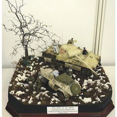 an army vehicle and tank on display in a glass case with snow all around it