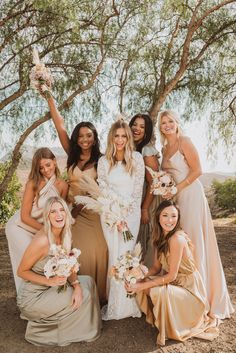 a group of women standing next to each other in front of a tree with flowers