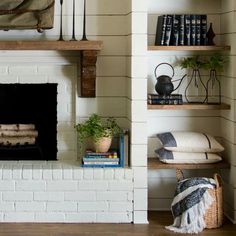 a living room with a fire place and bookshelves on the wall above it