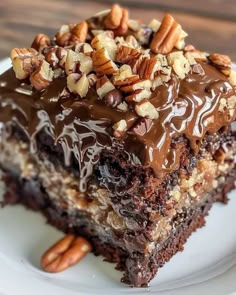 a close up of a piece of cake on a plate with chocolate frosting and nuts