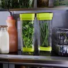 three plastic containers filled with vegetables and milk on top of a shelf in a kitchen