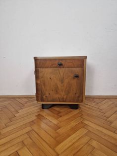 a wooden cabinet sitting on top of a hard wood floor next to a white wall