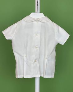 An elegant two-piece set for baby boys to wear during any special occasion. The top has a peter pan collar, handmade pleats, and short sleeves; it has buttons on the back for closure. The bottom is bubble-shorts with buttons on the sides for closure and an elastic band on the back. The interior, or lining, is made with cotton fabric, while the exterior is with off-white organza. Dry clean 2 piece set Interior: 100% cotton; exterior: 100% polyester Made in Spain Final Sale, no exchanges nor retur Classic White Collared Sets, Classic Short Sleeve Sets For Baptism, Classic White Tops With Sailor Collar, Classic White Top With Sailor Collar, Classic White Sailor Collar Top, White Short Sleeve Formal Sets, Baptism Outfits For Boys, Bubble Outfit, Bubble Clothes