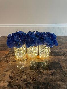 three vases filled with blue flowers on top of a table