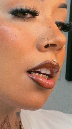 a woman with piercings on her face and nose is looking at the camera while wearing gold jewelry