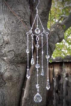 a wind chime hanging from the side of a tree in front of a fence