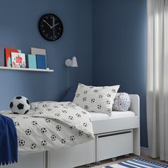 a soccer themed bedroom with blue walls and white bedding, along with a black clock on the wall