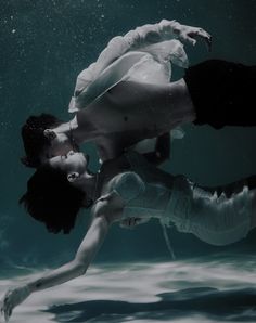 two people are floating in the water with their hands on each other's backs