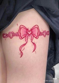 a woman's thigh with a pink bow and chain tattoo on the side of her leg