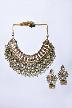 22kt gold plated mixed metal necklace with Mughal cut work pattern, crescent, floral drop tassels, enamel details, embellished kundan brass and white pearl drop tassel details. Paired with embellished chandbali jhumkas.
Components: 1 Necklace, Pair of Earrings
Type: Kundan Brass, Pearls Embellished and Enamelled
Composition: Mixed Metal
Color: Gold,White
Other Details: 
Mughal cut work pattern
Green enamel details
Dimensions L x B (in cms):
Necklace: 16 x 20
Earrings: 6.5 x 4
Closure:
Necklace: Mughal Pattern, Mixed Metal Necklace, Work Pattern, Metal Necklace, Jewellery Sets, Jewellery Set, Green Enamel, Cut Work, Mixed Metals