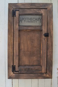 a wooden sign mounted to the side of a white wall with metal lettering that reads apothecary