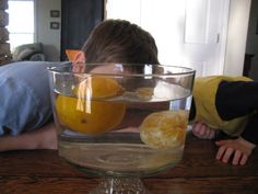 a boy laying on the floor next to a glass bowl filled with oranges