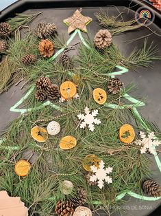 a christmas tree made out of oranges and pine cones on a tray with other decorations