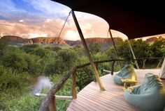 two bean bags sitting on top of a wooden deck next to a river and mountains