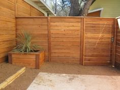 a wooden fence next to a house with a potted plant