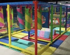 an indoor play area for children with colorful walls and netting on the sides, in a building