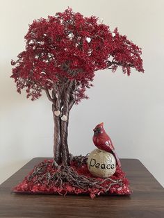 a red bird sitting on top of a rock next to a tree