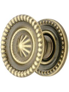 an antique brass door knob with a decorative design on the front and side, set against a white background