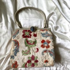 an old purse is laying on a white sheet with a blue button in the middle