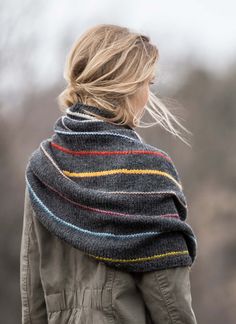 a woman with blonde hair wearing a gray jacket and multicolored striped shawl