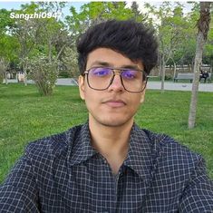 a man wearing glasses sitting in the grass